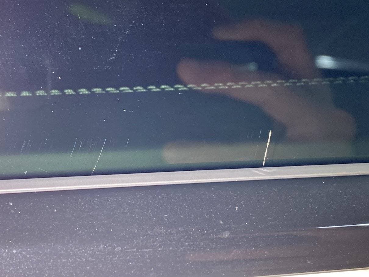 Light scratches visible on vehicle glass after tint installation.